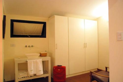 a bathroom with a white cabinet and a red suitcase at La Rozada Suites in Corrientes