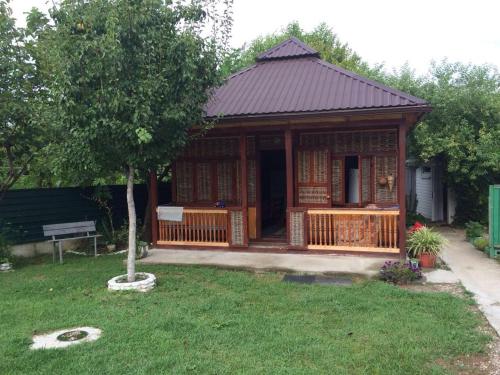 a small house with a porch and a tree at Guest House Chanba in Gudauta