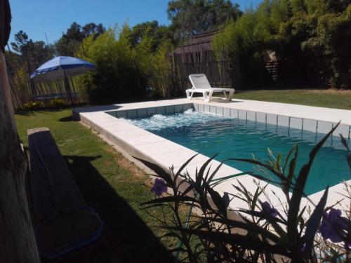 a swimming pool with a chair and an umbrella at El Nido in Sauce Viejo