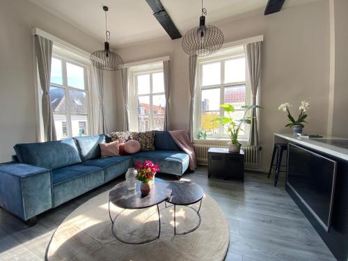 a living room with a blue couch and a table at Huize de Lekpoort - The City View - Historic Apartment in Vianen Center in Vianen