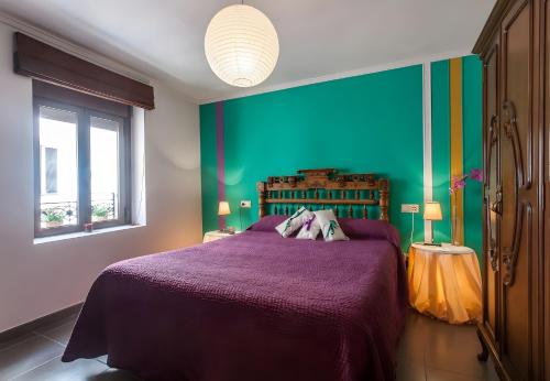 a bedroom with a purple bed and a green wall at Can Pitu in Alfondeguilla