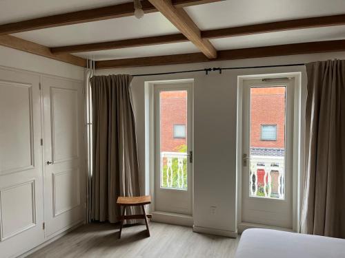 a bedroom with two doors and a chair and a window at Characteristic Dutch home in historic center Gouda in Gouda
