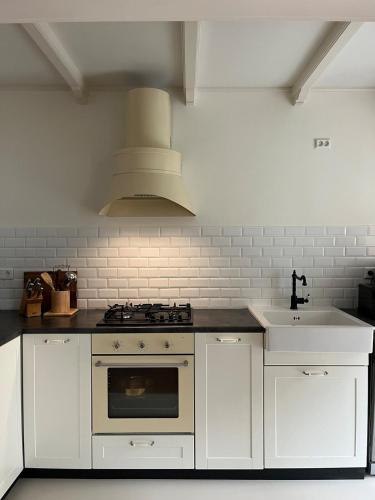 a white kitchen with a stove and a sink at Characteristic Dutch home in historic center Gouda in Gouda