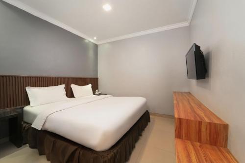 a bedroom with a bed and a tv on a wall at Barelang Hotel Nagoya Batam in Nagoya
