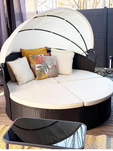 a wicker bed with pillows on top of it at La Cachette Fleurie in Hésingue