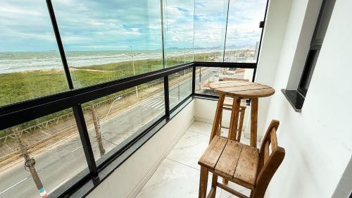 a balcony with a table and chairs and the ocean at ASA | Pé na Areia | Frente-Mar Meia Praia | 2 Qtos in Navegantes