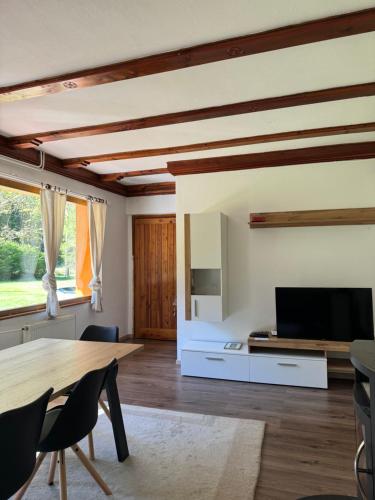 a living room with a table and a tv at Cozy Mountain Stay near Kranjska Gora in Gozd Martuljek