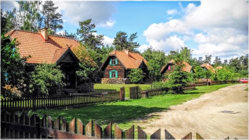 a house with a fence in front of a yard at Kiermusy Dworek nad Łąkami in Kiermusy
