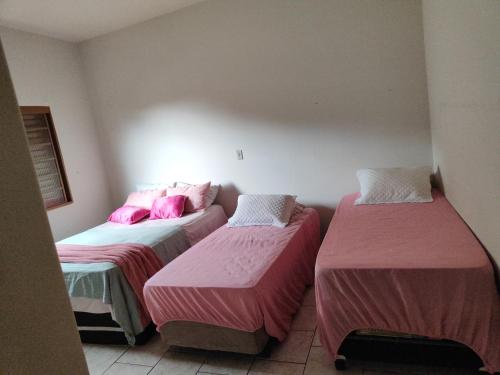 drie bedden in een kamer met roze en witte lakens bij POUSADA ELSHADAY Centro in Osvaldo Cruz