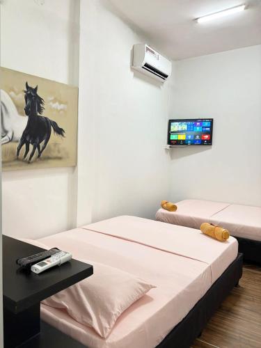 Ein Zimmer mit zwei Betten und einem Fernseher an der Wand. in der Unterkunft Hotel 7 in Cúcuta
