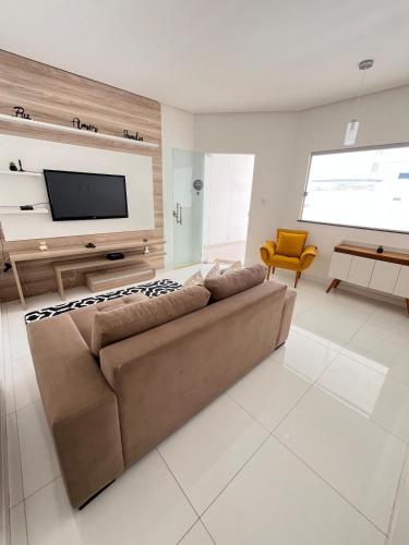 a living room with a couch and a flat screen tv at Refúgio Fraga Maia com Piscina e Estacionamento in Santo Antônio dos Prazeres