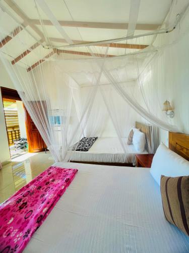 a bedroom with a white bed with a pink blanket on it at Racy Nature Cottage in Ella