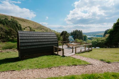 a building with a table and benches on a field at Reservoir View Micro Cabin in Dol-y-gaer Station