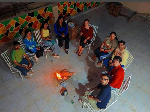 a group of people sitting in chairs around a fire at The Pink Nest - Backpackers Abode in Jaipur