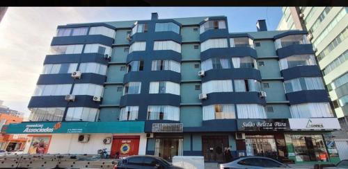 a blue building with cars parked in front of it at Entre o Mar e o Centro - A melhor Localização in Torres