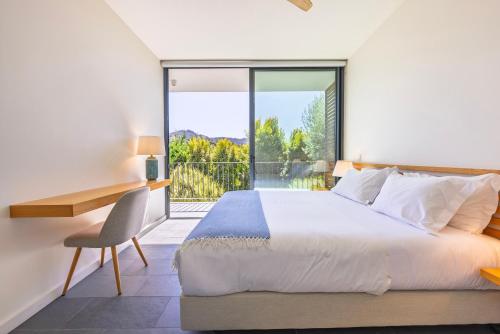 Un dormitorio con una cama y un escritorio y una ventana. en Casa de Cima Luxury Villa, en Sintra