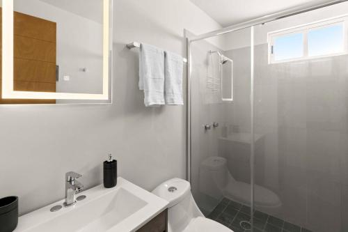 a white bathroom with a sink and a shower at Centrally located and comfortable apartment! in Cabo San Lucas