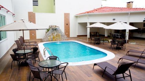 una piscina con mesas y sillas y un tobogán en Pousada Apatej, en Peruíbe