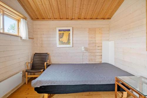 een kleine slaapkamer met een bed en een stoel bij 1069-Thisted-Kobbelsti-23 in Klitmøller
