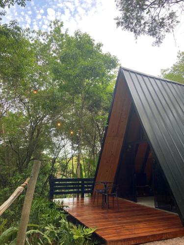 a cabin with a wooden deck in the woods at Sítio Aroeira Cabanas in Sao Jorge