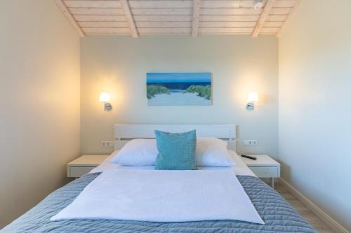 ダゲビュルにあるNordseeperleの大きな白いベッドと青い枕のある寝室