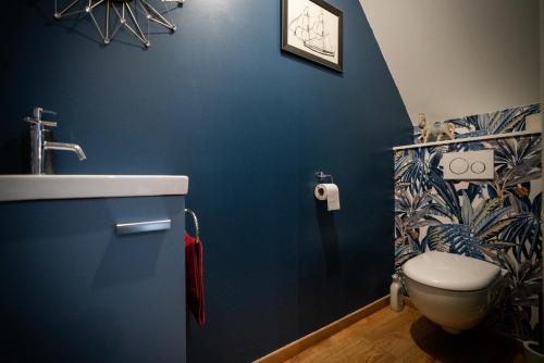 Un baño azul con lavabo e inodoro. en Chambres d'hôtes - Sur le plateau des landes, en Helfaut