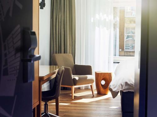 a room with a chair and a table and a window at Swissôtel Amsterdam in Amsterdam