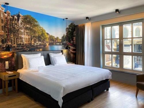 a bedroom with a large bed with a painting of a canal at Swissôtel Amsterdam in Amsterdam