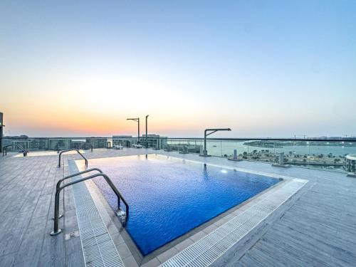 a swimming pool with a view of the ocean at Champions' Apartment - Balcony Sunsets - Rooftop Pools - Modern Oasis - Family Heaven - Full Canal Views - 2 min walk from Space42 Arena in Abu Dhabi