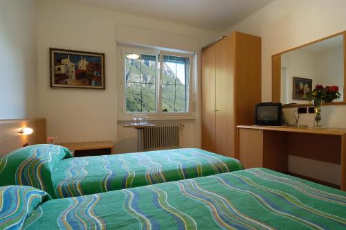 a hotel room with two beds and a window at Hotel Karinhall in Trento