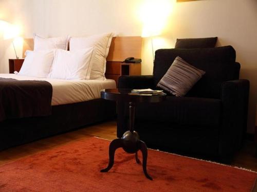 a bedroom with a bed and a couch and a table at Hotel Mestre de Avis in Guimarães
