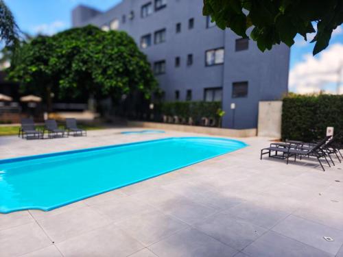 a swimming pool with chairs and a building in the background at Iguassu Express Hotel in Foz do Iguaçu