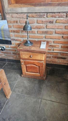 a lamp on a wooden table in front of a brick wall at alojamiento Villa sarita in Posadas