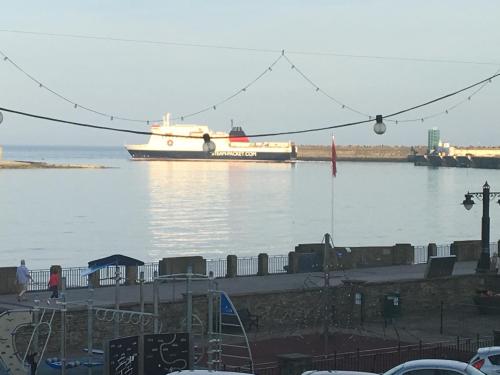 a large boat in the water with people walking on a dock at Cubbon House in Douglas