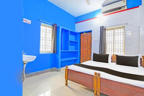 a bedroom with blue walls and a bed in a room at Hotel O New Cuttack Guest House in Cuttack