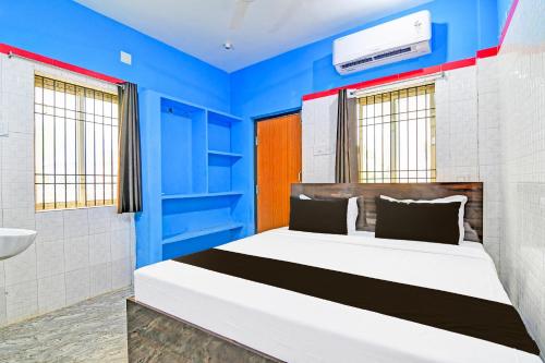 a bedroom with a bed with blue walls at Hotel O New Cuttack Guest House in Cuttack