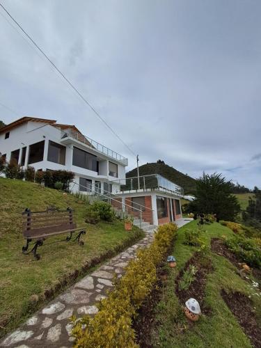 a house on a hill with a bench in front of it at Suit Encanto Dorado in Guatavita