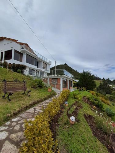 a house on a hill with a bench and a building at Suit Encanto Dorado in Guatavita