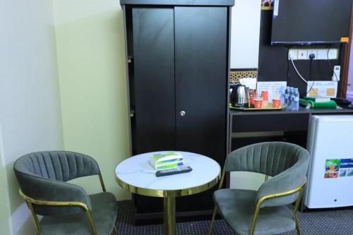 Cette chambre comprend une table, des chaises et un comptoir. dans l'établissement فندق جواد الحرم الفندقية, à Az Zahrāʼ