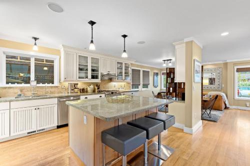 a kitchen with white cabinets and a island with bar stools at Pleasure Point Surf Retreat in Santa Cruz
