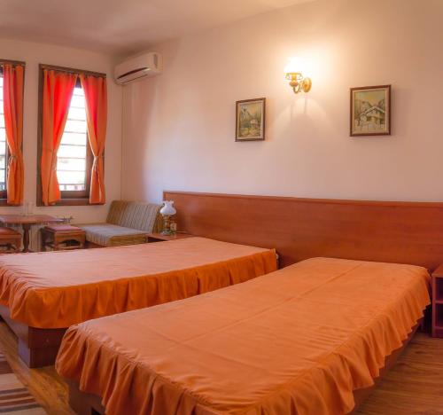 two beds in a room with orange sheets at Sivrieva House in Zlatograd