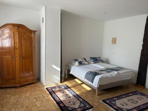 a bedroom with a bed and a cabinet and two rugs at La Belle Mélusine in Bergheim