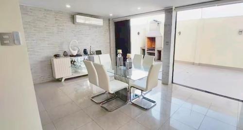 a dining room with a glass table and white chairs at Stylish Home via a Samborondon in Estancia Vieja