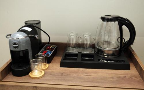 a counter with a coffee maker and glasses on it at A Gallery Hotel in Shkodër