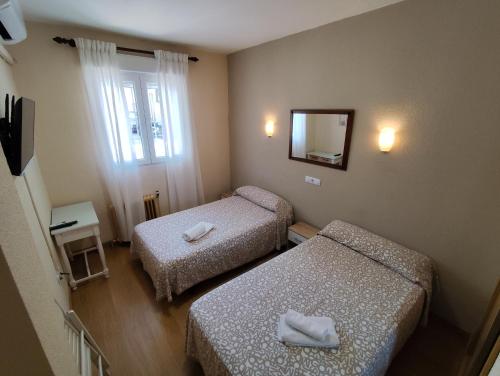 a small room with two beds and a mirror at Hostal Hernan Cortes in Cáceres