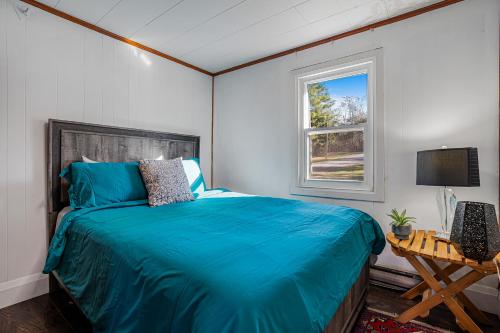 a bedroom with a blue bed and a window at Rustic Lakefront Cottage with Fire Pit & Scenic Views in Brechin