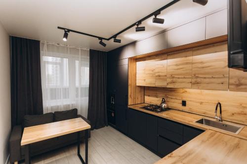 a kitchen with black cabinets and a wooden counter top at Luxury Apartment Lushpy Avenue - Hotel Standard in Dobrovelychkivka