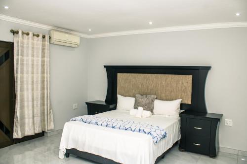 a bedroom with a large bed with a black headboard at Silver Lake Lodge Rustenburg in Rustenburg