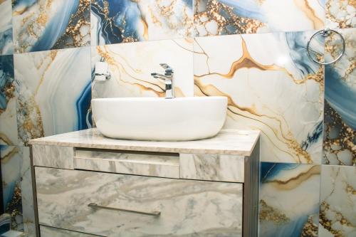 a bathroom with a sink and a marble wall at Silver Lake Lodge Rustenburg in Rustenburg