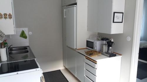 a small kitchen with white cabinets and a microwave at Apartment Vuorikatu 35 in Kuopio